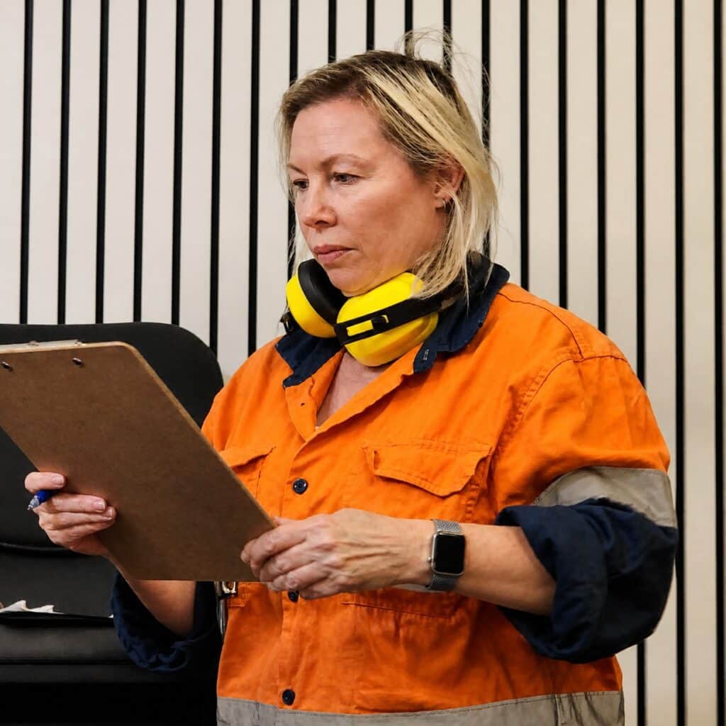 Lisa Withers, in a high-vis outfit. is a maintenance worker looking at her worksheet.